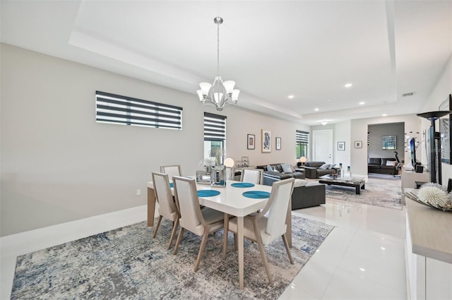 tiled dining area featuring a tray ceiling and a chandelier