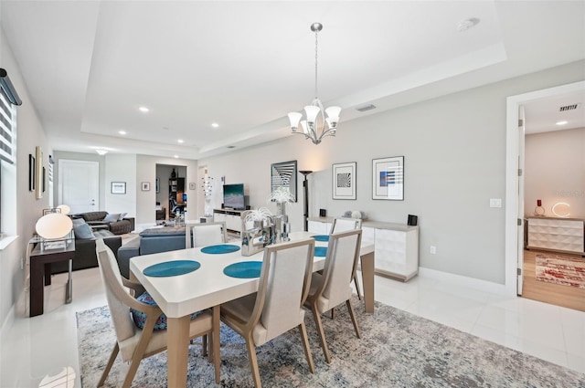 dining space featuring light tile patterned floors, a tray ceiling, and a chandelier