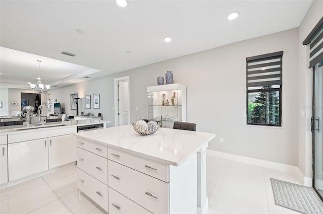 kitchen with a center island, decorative light fixtures, white cabinetry, sink, and light tile patterned flooring