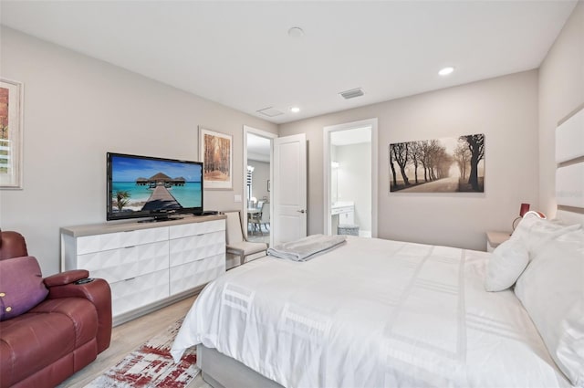 bedroom featuring ensuite bath and light wood-type flooring