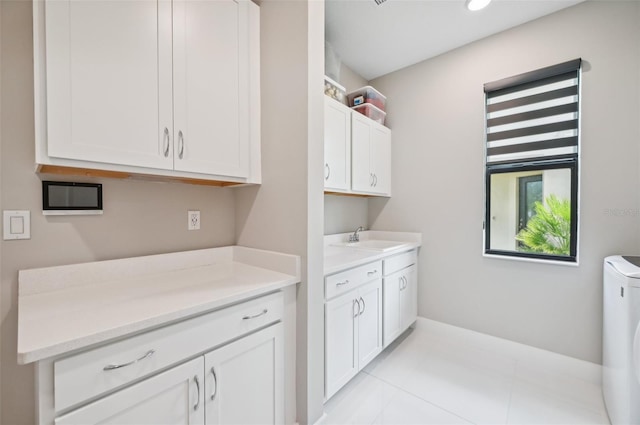 clothes washing area featuring cabinets, washer / dryer, sink, and light tile patterned flooring