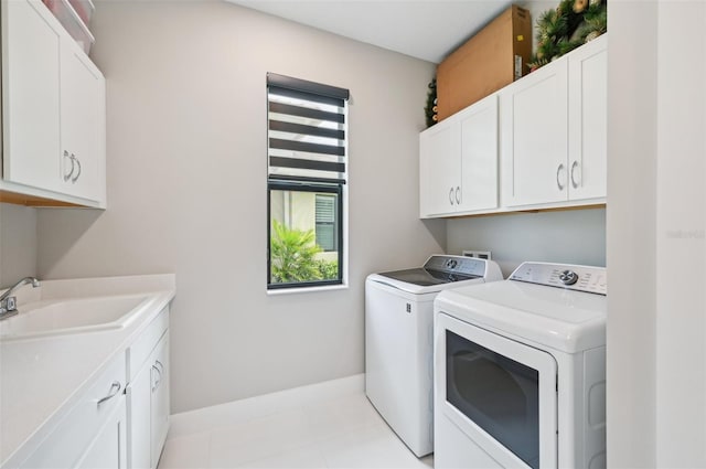 clothes washing area with washer and clothes dryer, sink, and cabinets