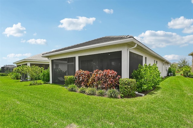 view of side of home with a sunroom and a yard