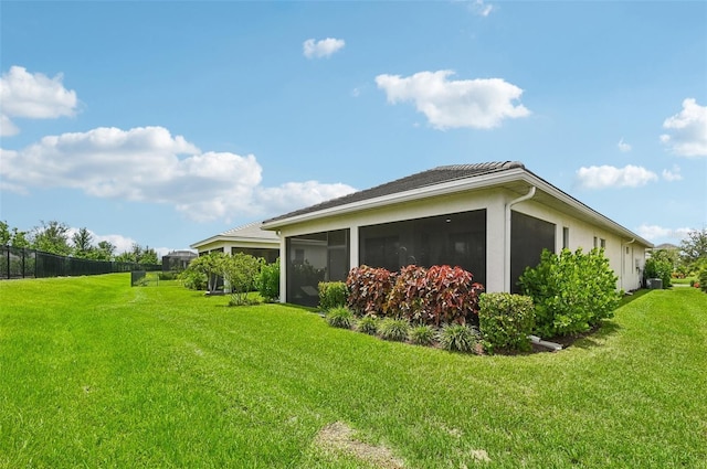 view of side of home with a sunroom and a lawn