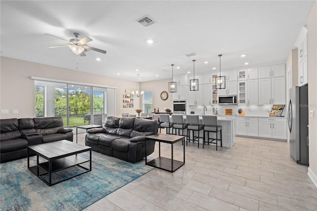 living room featuring sink, ceiling fan with notable chandelier, and a textured ceiling