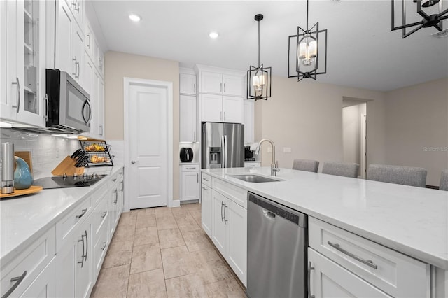 kitchen featuring pendant lighting, sink, a breakfast bar area, stainless steel appliances, and white cabinets