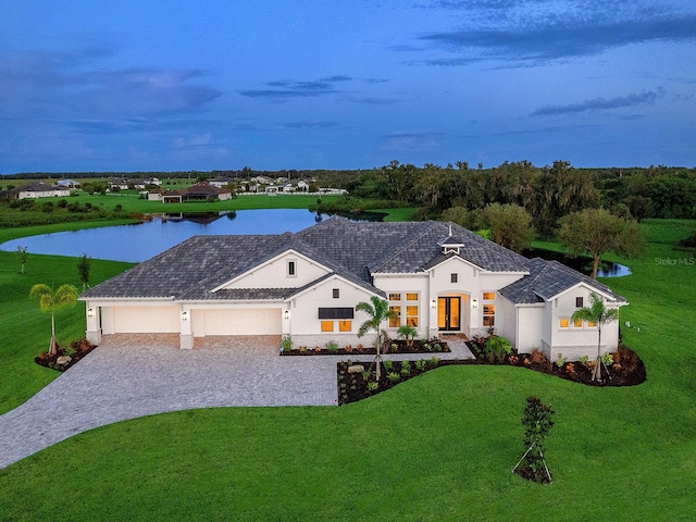 view of front of property with a front yard, a water view, and a garage