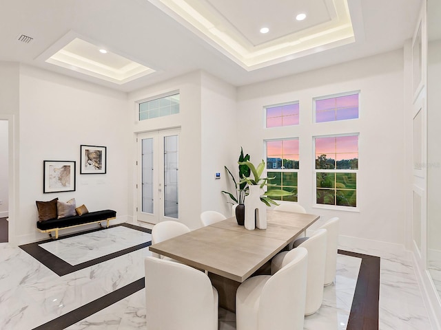 dining area with a tray ceiling, french doors, and a high ceiling