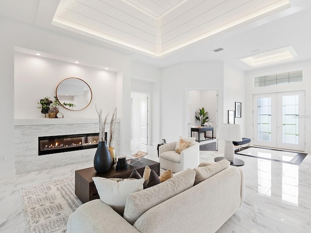 living room with a raised ceiling, a high ceiling, and french doors