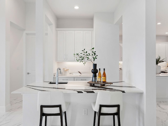 kitchen with a kitchen breakfast bar, kitchen peninsula, sink, and white cabinets