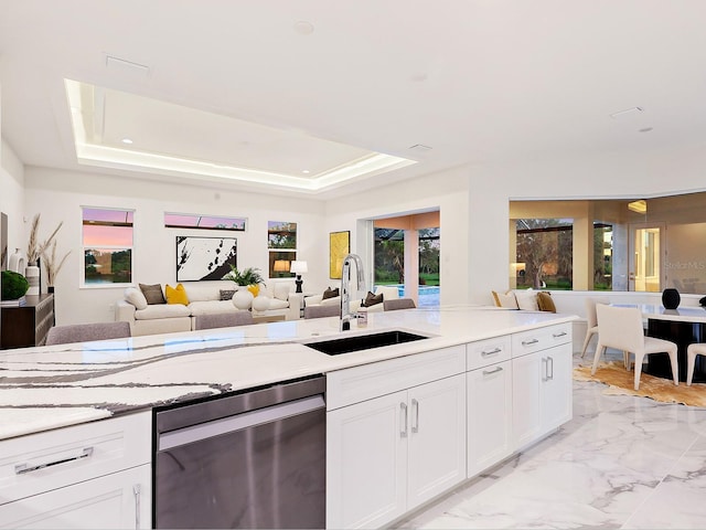 kitchen featuring stainless steel dishwasher, white cabinetry, sink, and a tray ceiling