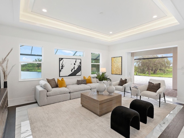 living room with a water view and a raised ceiling