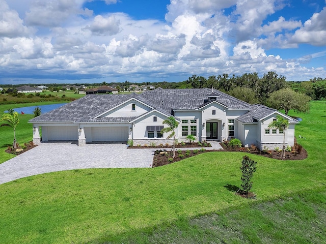 ranch-style home with a garage, a water view, and a front lawn