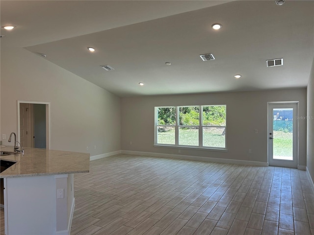 unfurnished living room featuring a wealth of natural light, visible vents, a sink, and baseboards