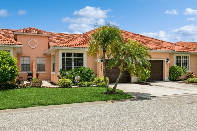 mediterranean / spanish home with a garage and a front lawn