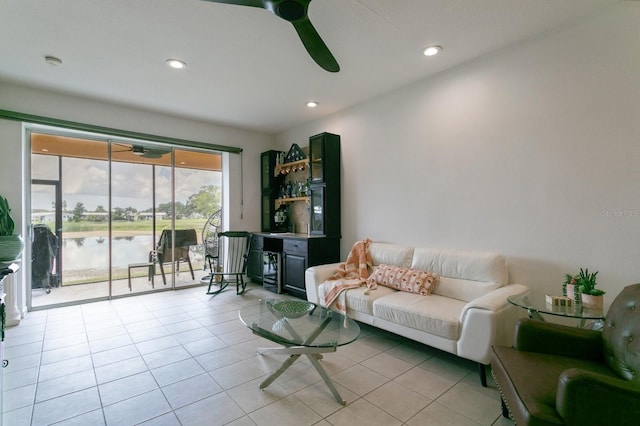 tiled living room with a water view and ceiling fan