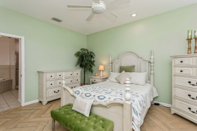 bedroom with ensuite bathroom, light tile patterned floors, and ceiling fan