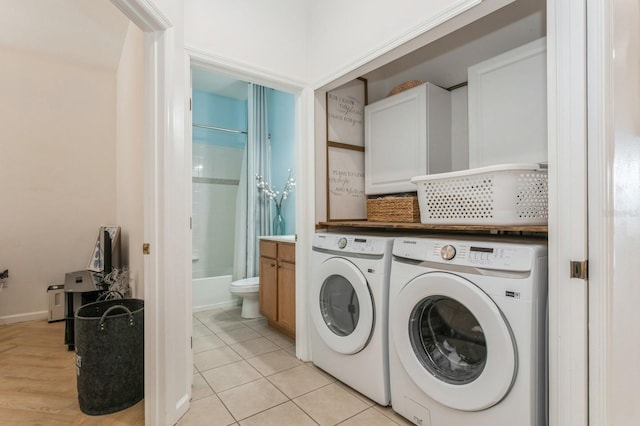 washroom with cabinets, light wood-type flooring, and washing machine and clothes dryer