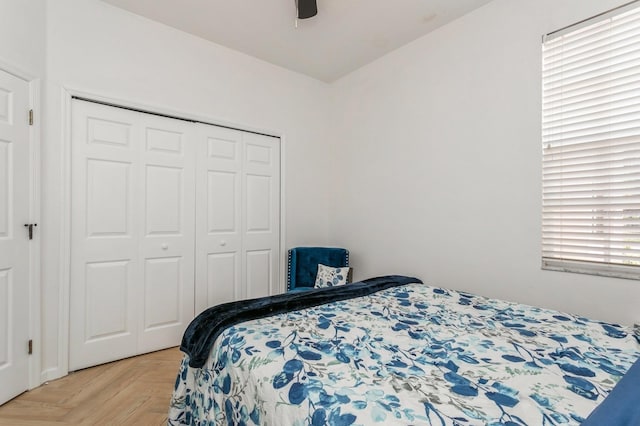 bedroom featuring light parquet floors, multiple windows, ceiling fan, and a closet