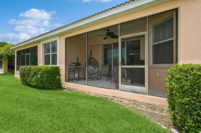 rear view of house featuring ceiling fan and a yard