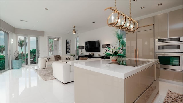 kitchen with pendant lighting, a center island, ceiling fan with notable chandelier, black electric cooktop, and stainless steel double oven