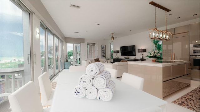 dining area featuring light tile patterned floors and ceiling fan with notable chandelier