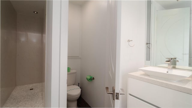 bathroom with tiled shower, vanity, and toilet