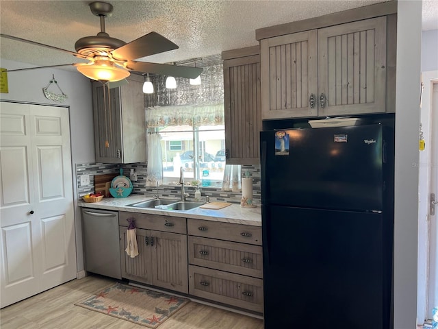 kitchen featuring backsplash, dishwasher, light hardwood / wood-style floors, sink, and black refrigerator