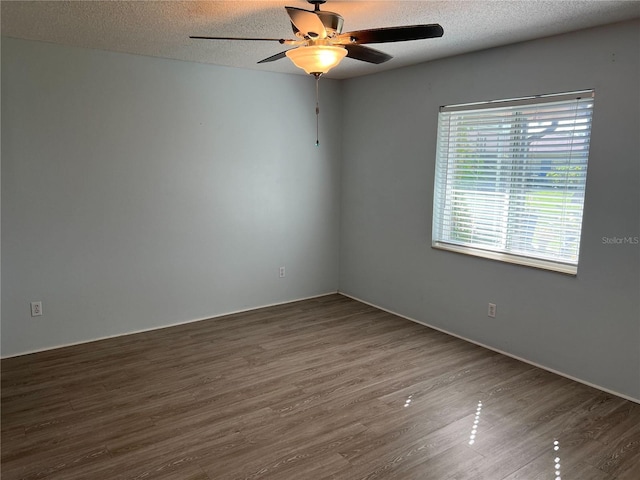 spare room featuring a textured ceiling and dark hardwood / wood-style flooring