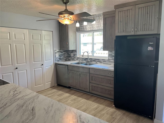 kitchen with black refrigerator, decorative backsplash, a textured ceiling, stainless steel dishwasher, and sink