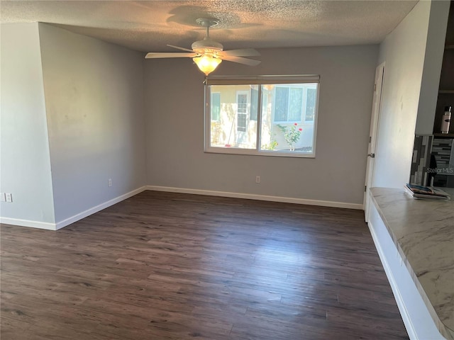 spare room with a textured ceiling, ceiling fan, and dark hardwood / wood-style flooring