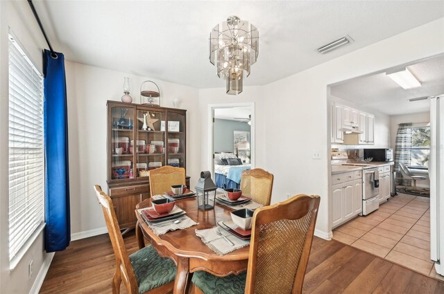 dining space with ceiling fan with notable chandelier and light wood-type flooring