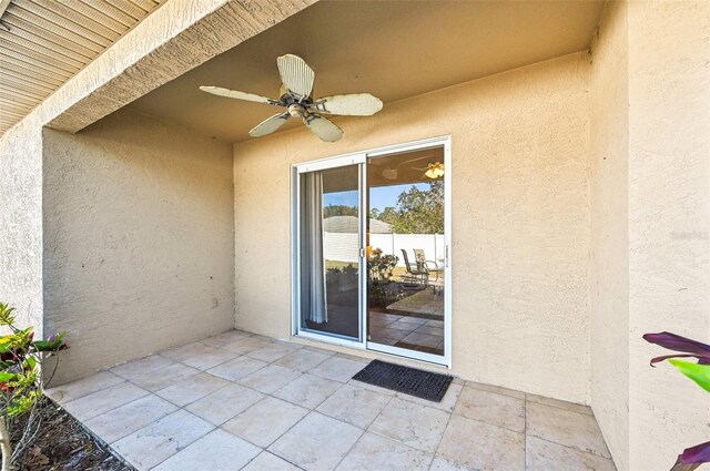 view of exterior entry with ceiling fan and a patio