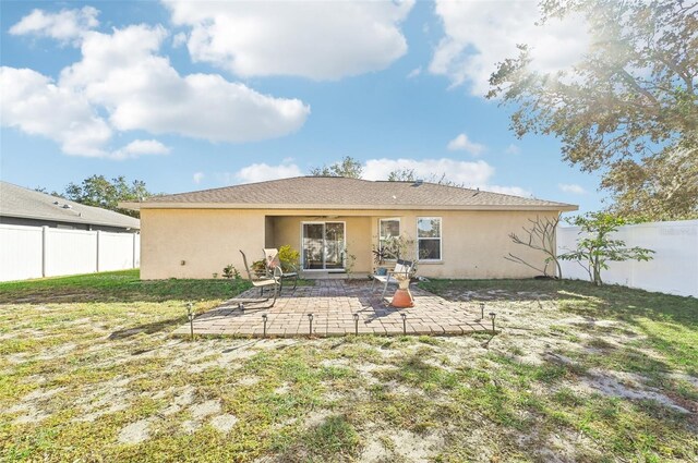 back of house featuring a lawn and a patio