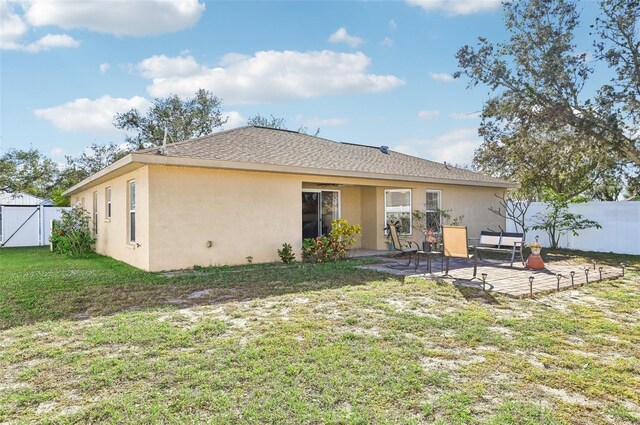 back of property with a yard and a patio