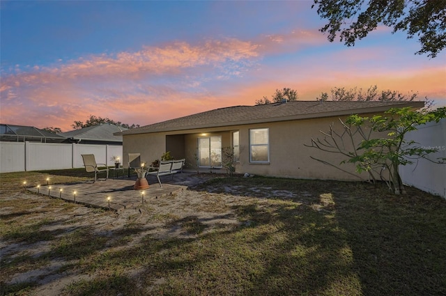 back house at dusk with a yard and a patio