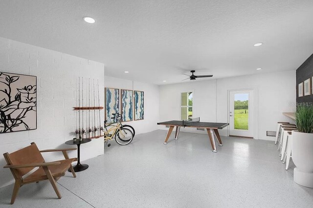 recreation room with ceiling fan and a textured ceiling