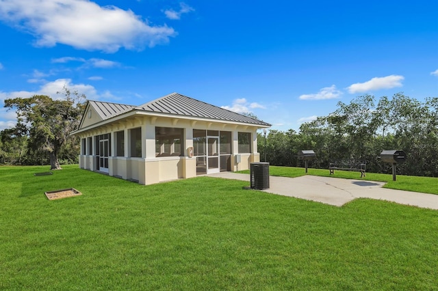 back of property featuring a sunroom, cooling unit, and a lawn