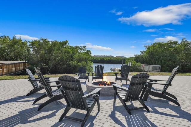 wooden deck with a water view, a patio area, and an outdoor fire pit