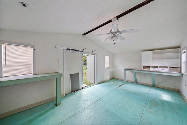 empty room with ceiling fan, vaulted ceiling, and a textured ceiling