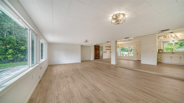 unfurnished living room with light hardwood / wood-style flooring, brick wall, and sink