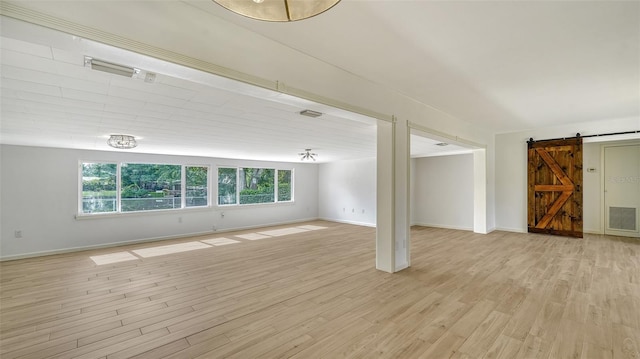 unfurnished living room with light hardwood / wood-style flooring and a barn door