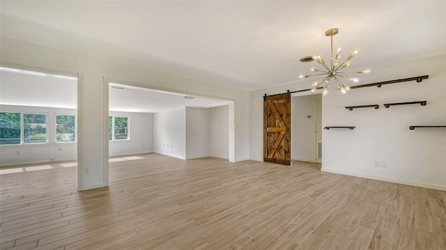 unfurnished living room featuring an inviting chandelier, light wood-type flooring, and a barn door