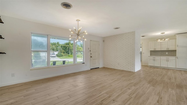 unfurnished dining area featuring a notable chandelier and light wood-type flooring