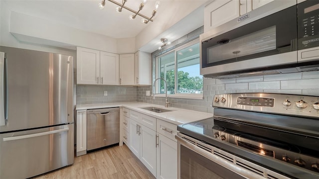 kitchen with white cabinetry, light hardwood / wood-style flooring, backsplash, appliances with stainless steel finishes, and sink