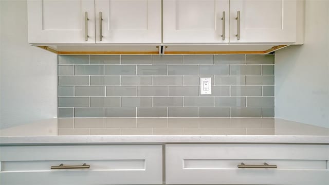 interior space featuring white cabinetry, light stone countertops, and backsplash