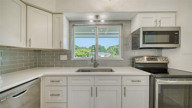 kitchen featuring appliances with stainless steel finishes, white cabinetry, backsplash, and sink