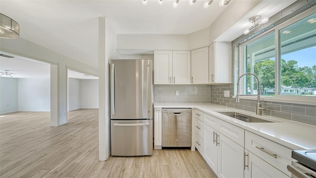 kitchen featuring appliances with stainless steel finishes, light hardwood / wood-style flooring, white cabinets, sink, and backsplash