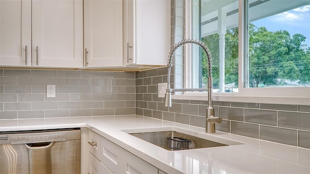 kitchen featuring stainless steel dishwasher, tasteful backsplash, a healthy amount of sunlight, and white cabinets