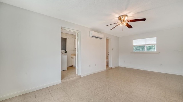 spare room with ceiling fan, washer / dryer, an AC wall unit, electric panel, and light tile patterned floors